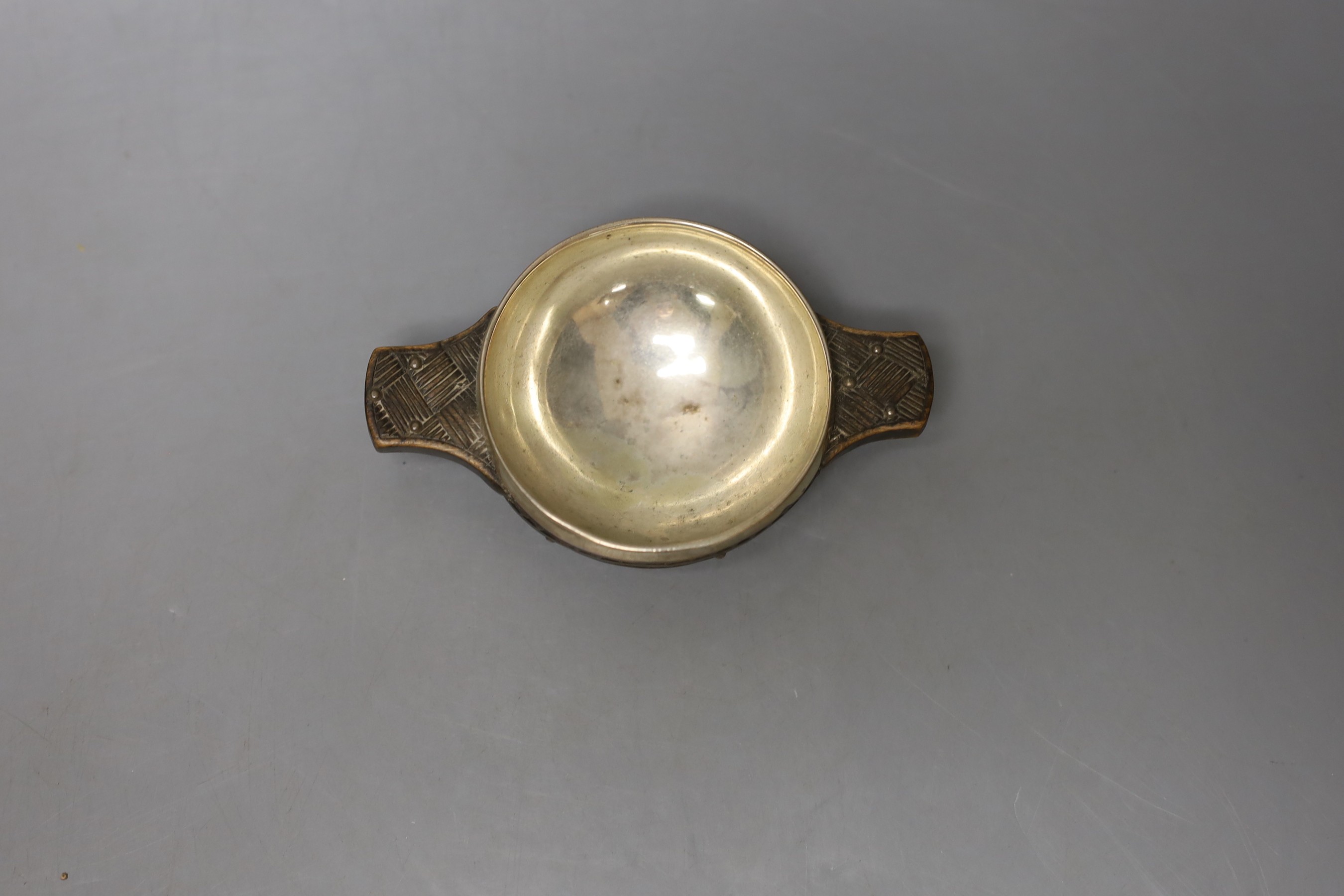 A late 18th/early 19th century white metal mounted wooded quaich, with interwoven carving, unmarked, diameter 11.1cm, (a.f).